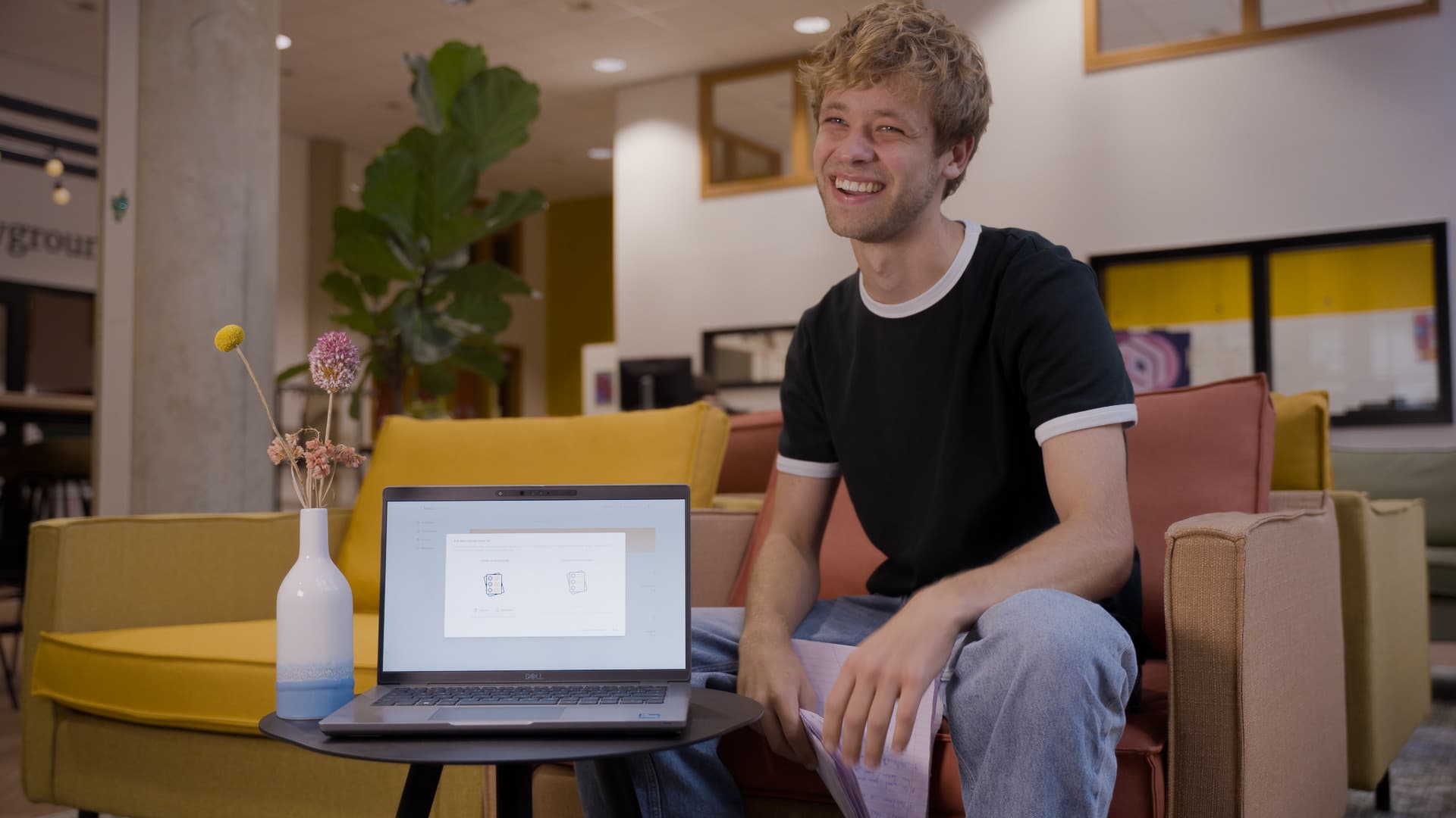 Kars, mede-oprichter van ToetsTester, glimlachend achter een laptop in een moderne kantooromgeving